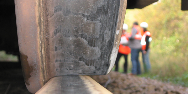 Train wheel on rail, workers in vests blurred background