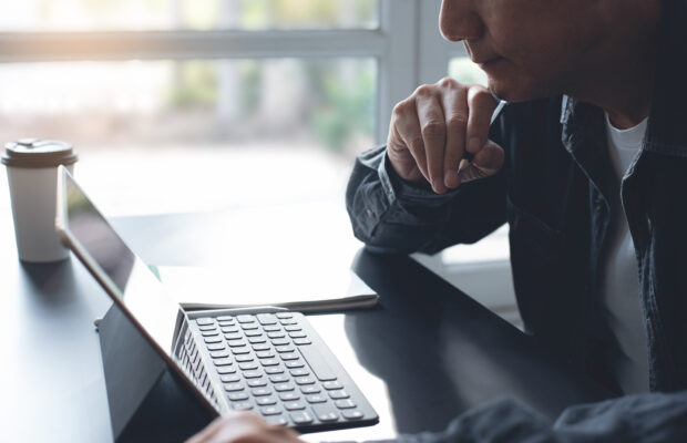 Person reading tablet holding a pencil in his hand