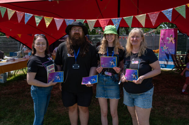 4 STEM ambassadors, smiling at camera and holding code challenge flyers