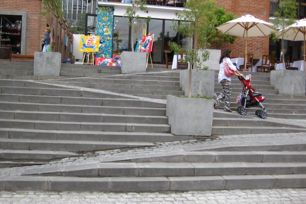Stair with built in ramp being used by person with pushchair.