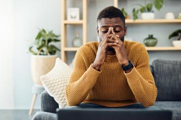 Shot of a young black man looking stressed out at home