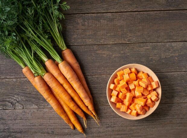 A table with carrots lying on them, both whole and chopped
