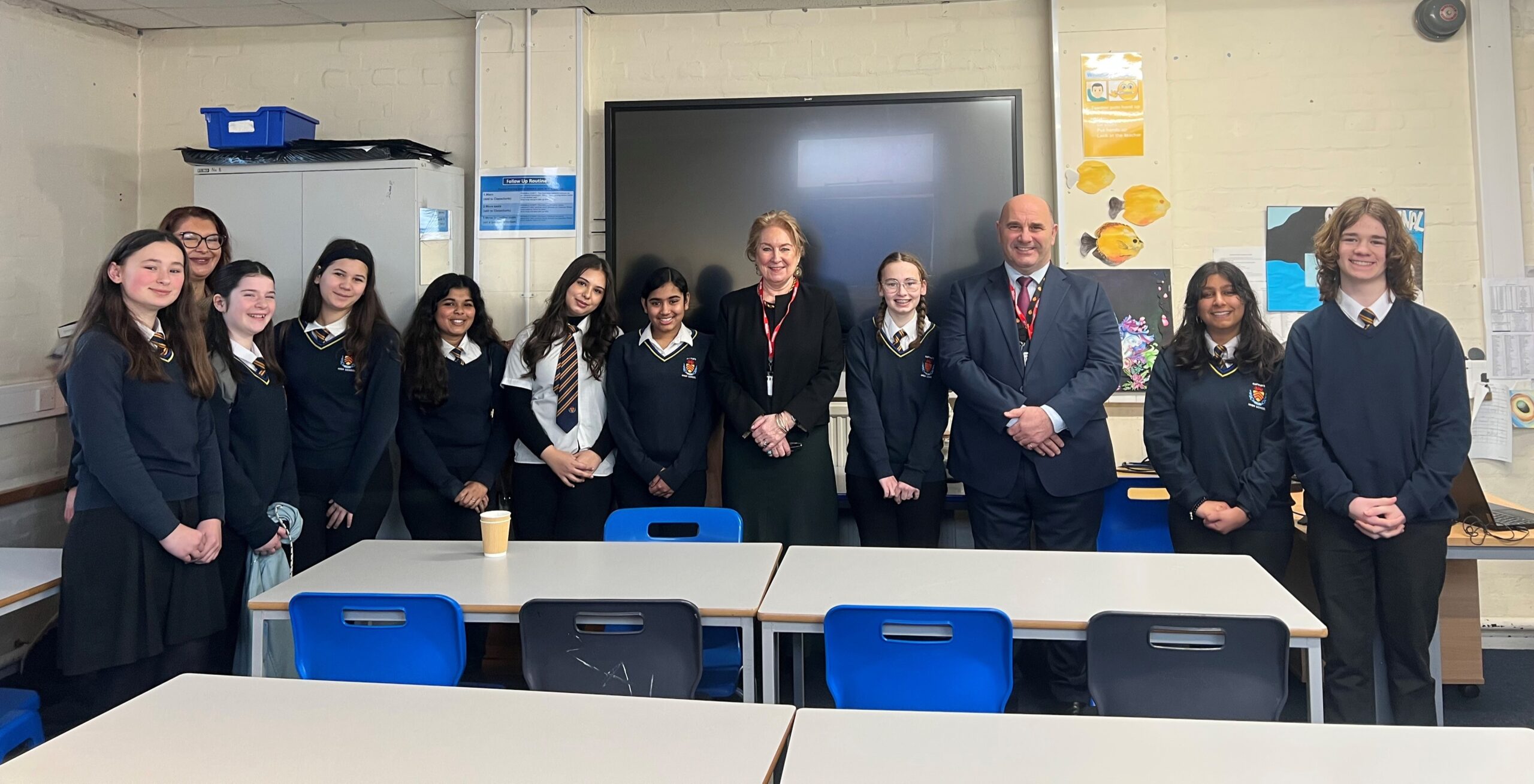 Lady Chief Justice in a school classroom, with school pupils and a teacher standing with her