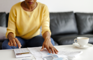 Person sitting at coffee table sorting through paper bills