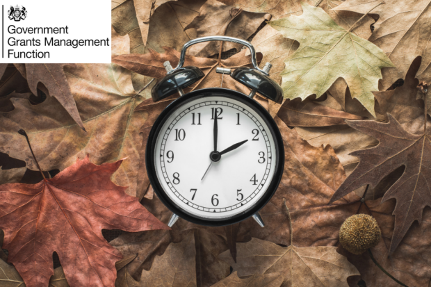Classic analogue alarm clock reclining amongst fallen leaves to signify the clocks changing to mark the end of British Summer Time (30 October 2022)