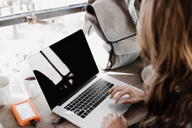 Woman sitting at a desk by a window, using a laptop.