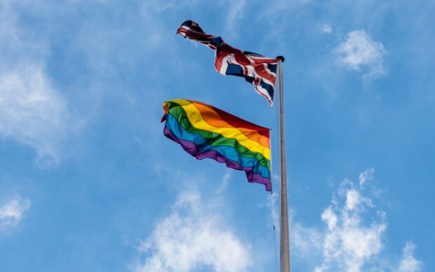 A pride flag and the Union flag flying on a flag pole above the Department for International Development