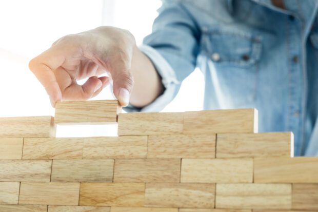 Hand of engineer playing a blocks wood tower game (jenga)