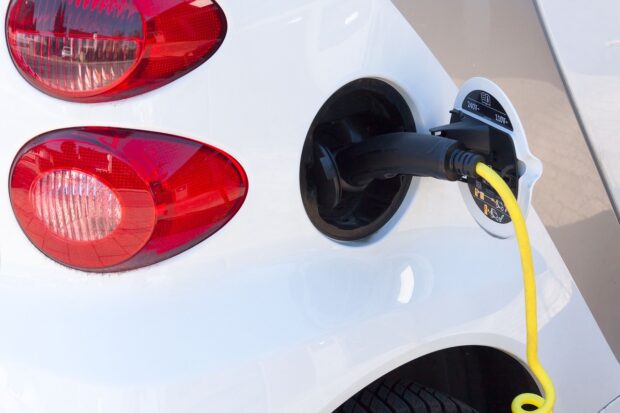 close up of a white car being charged with electrical cable