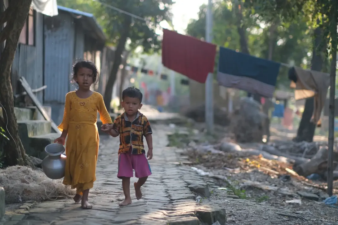 Children walking along a path with a bucket