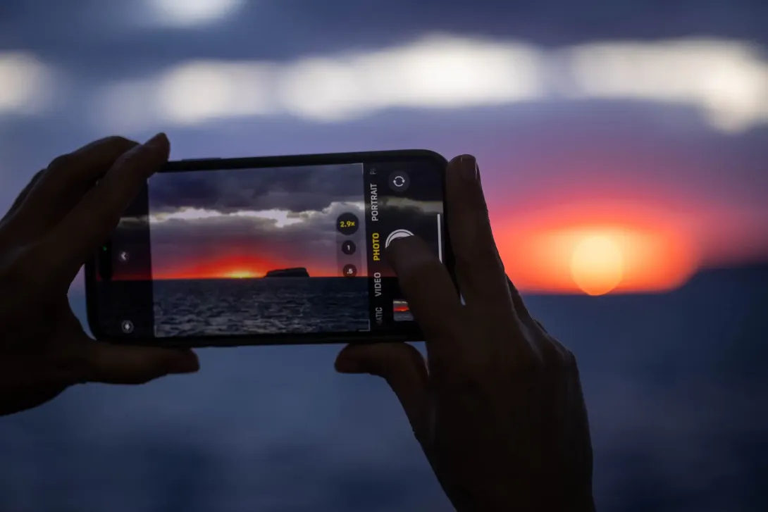 Person taking a photo of the sunset on a phone