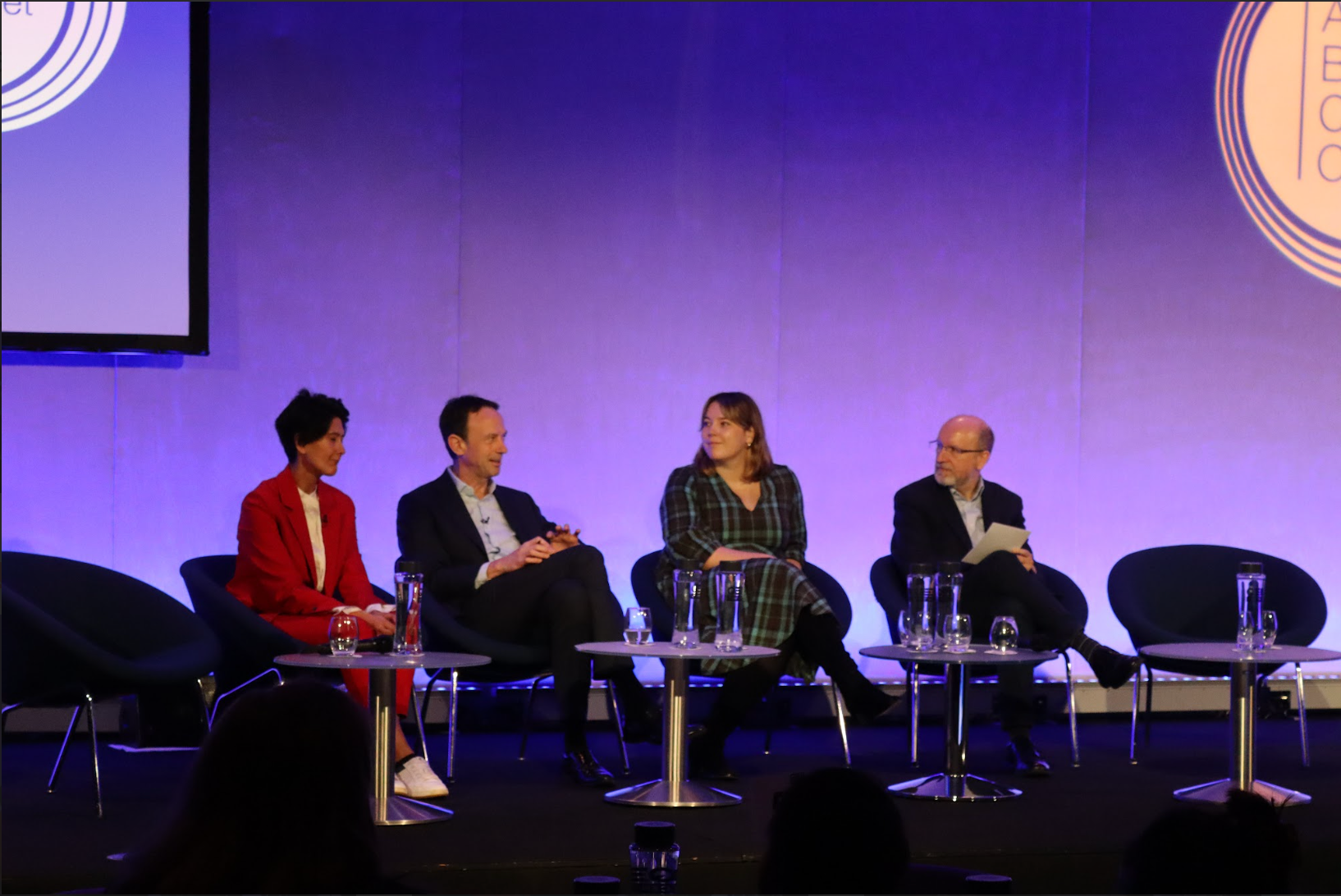 i.AI (Victoria Bew) on stage sitting down with Cat Little, Alex Chisholm and David Knott