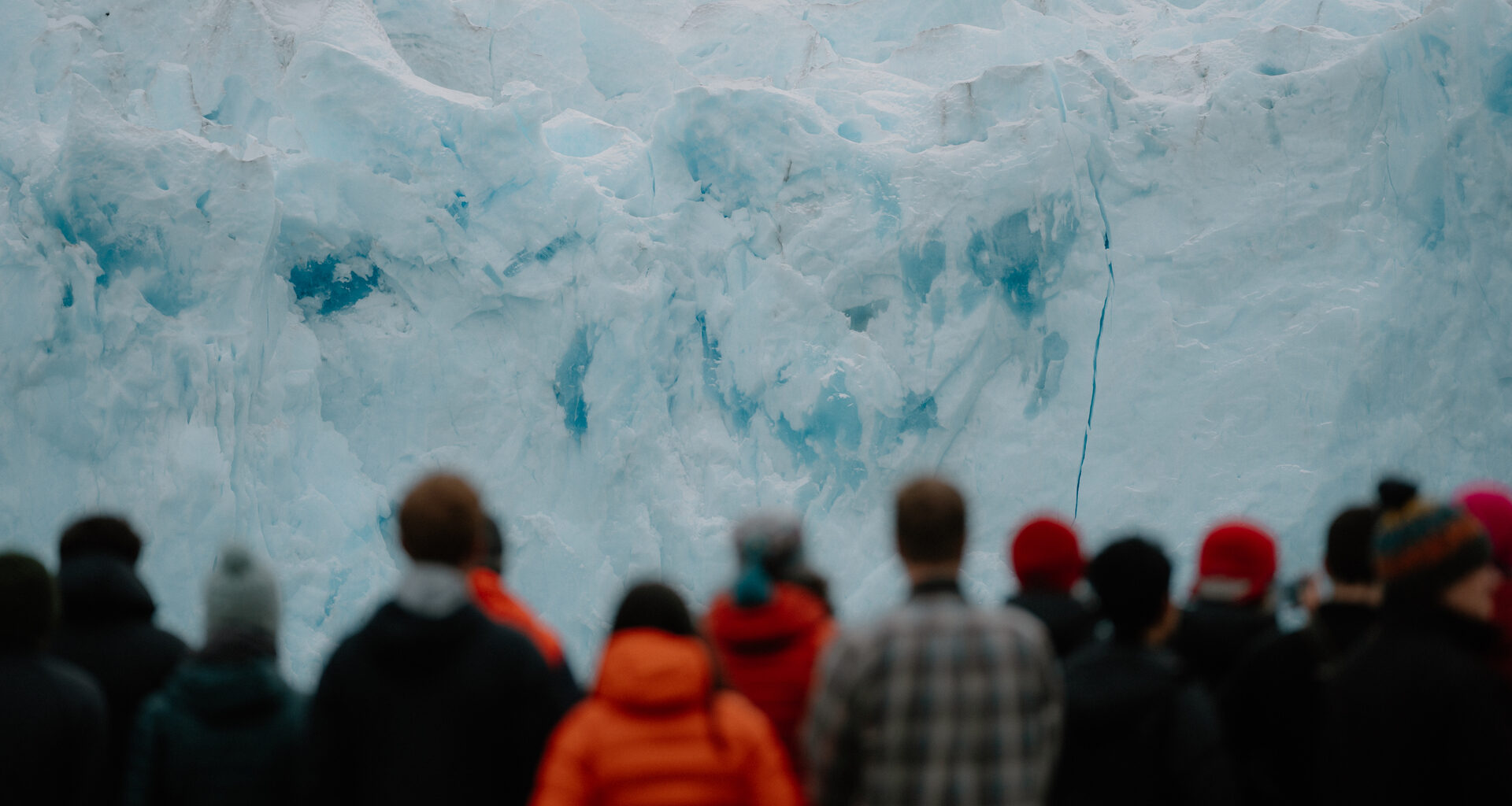 A group of people standing in front of a glacier