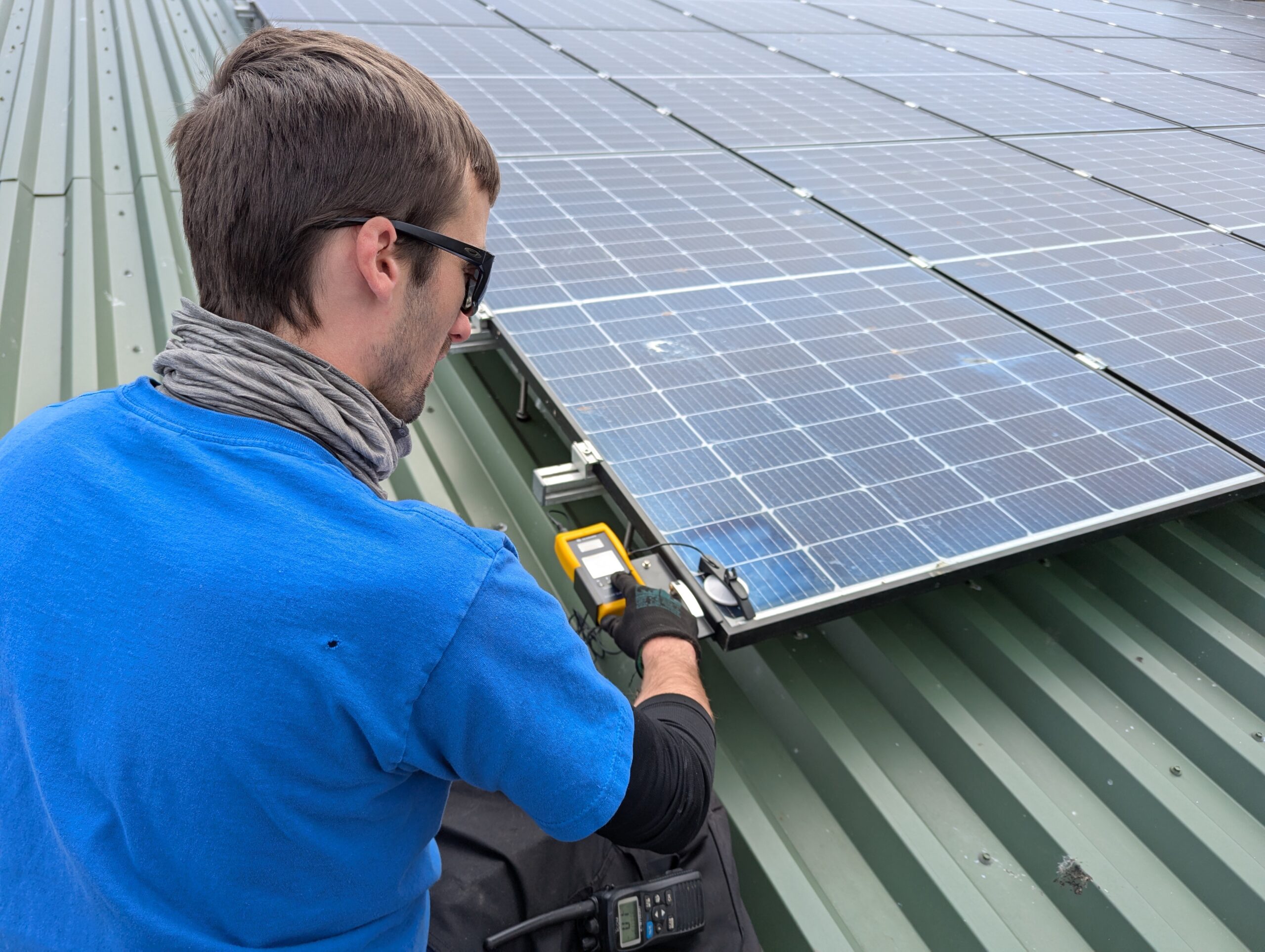 A man in a blue shirt looking towards a solar panel on a roof