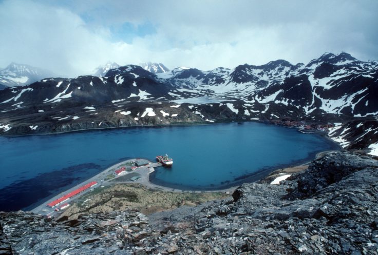 A body of water with a mountain in the background.