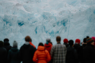 A group of people standing in front of a glacier