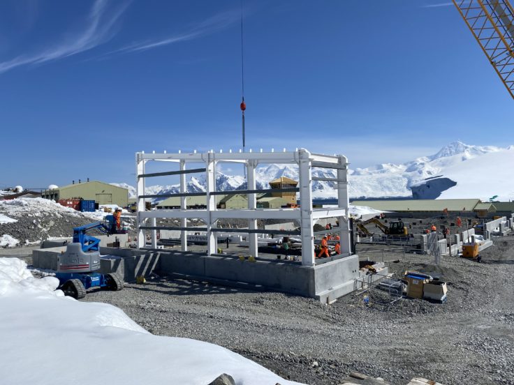 Steel frame of building being inserted onto construction site