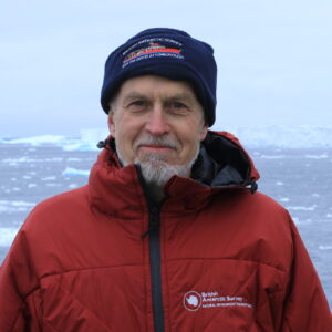 A man wearing a hat standing next to a body of water