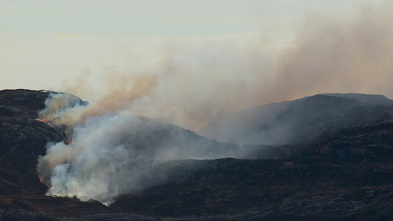 smoke billowing from a dark moorland landscape