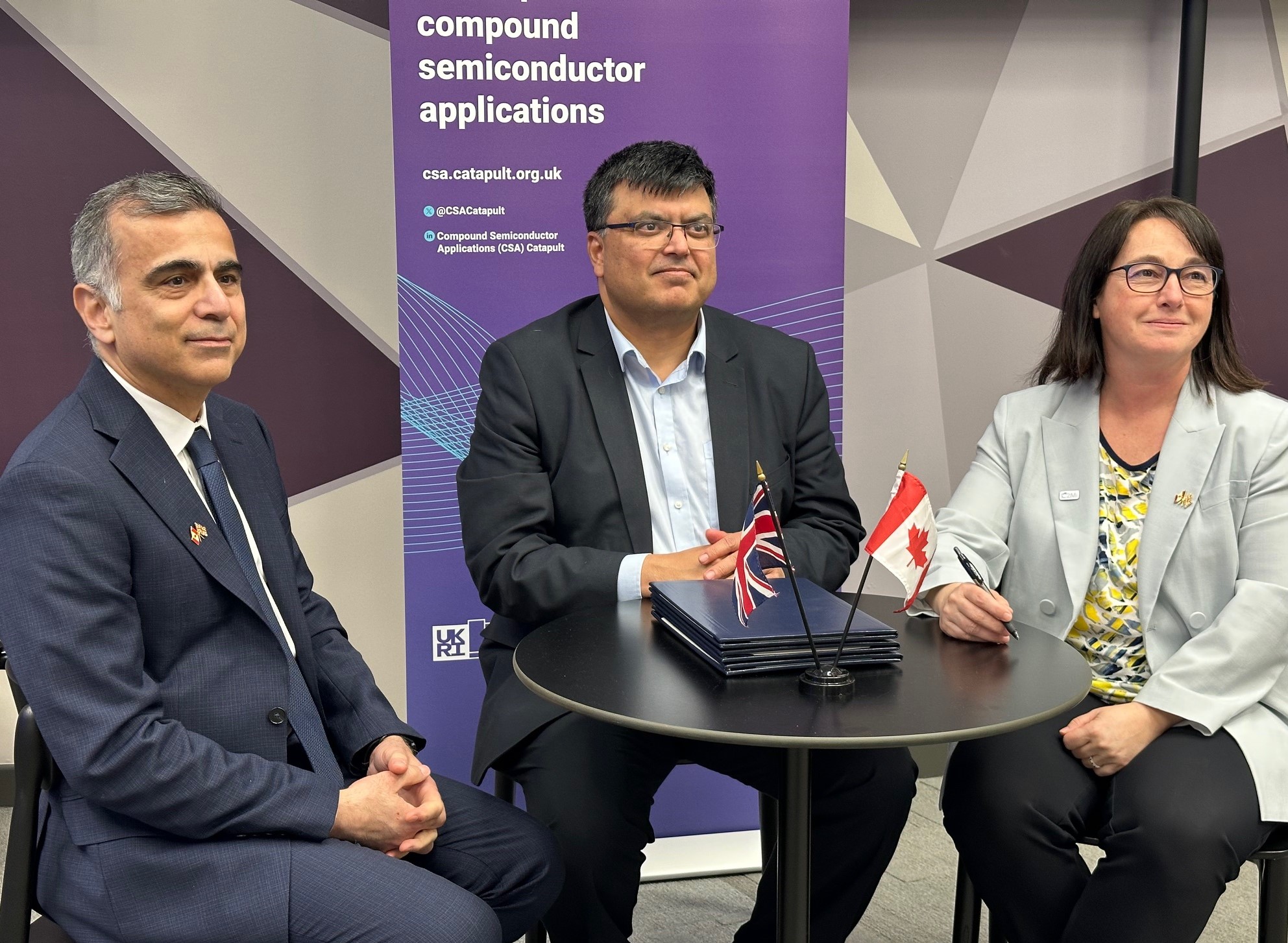 Nick Singh, Marie-Josée Turgeon, and Mitch Davies sit at a table with UK and Canadian flags before a CSA banner. - CSA Catapult