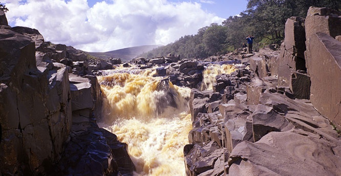 High Force, Teesdale. Quartz-dolerite (Whin Sill) at lip of High Force, looking upstream. Noon Hill can be seen in the background.