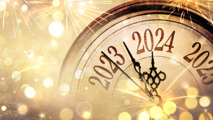 A clock showing the transition from 2023 to 2024 surrounded by bright fireworks and golden bokeh lights.