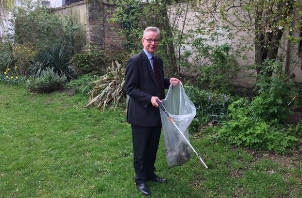 Image of Environment Secretary holding a rubbish bag collecting litter