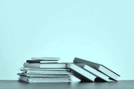 Stack of published advisory committee reports and documents on a desk.