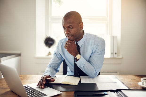 Man sitting at a desk in an office looking at a computer