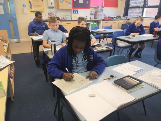 Primary school pupil working at a desk in a classroom