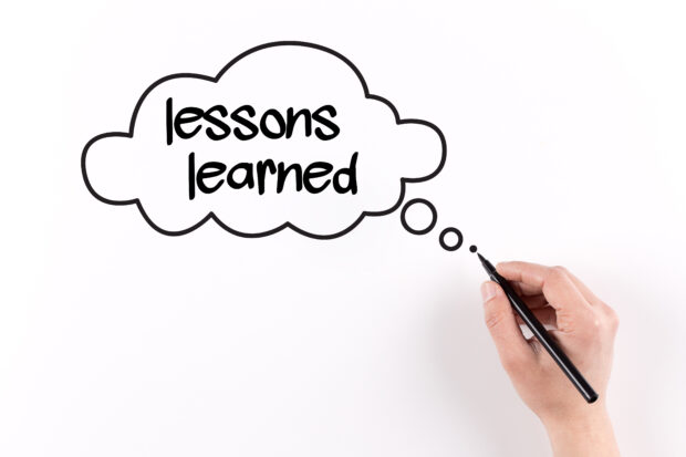Hand writing Lessons learned on white paper, View from above