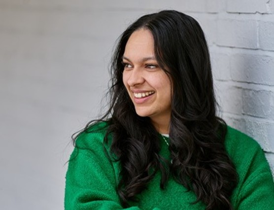 A woman in a green top smiling away from the camera