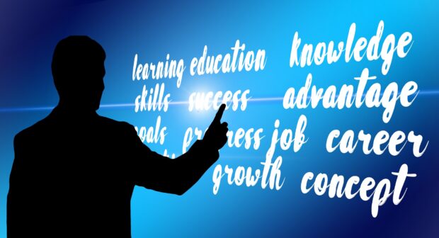 Person pointing to a board with the words: learning, education, sklls. success, growth, job, growth