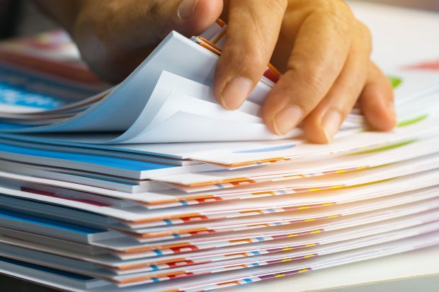 Decorative picture of a hand sifting through a pile of reports