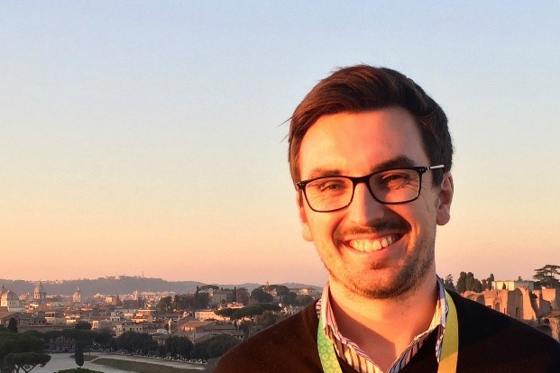 Daniel standing on a balcony with his back to rome.