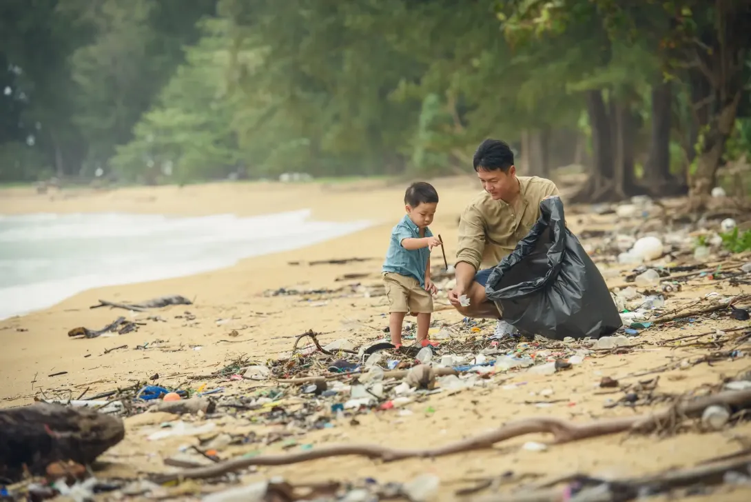 Man and a boy litter picking on a beach