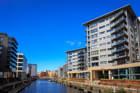 A residential block with eight storeys that are lived in, with balconies, overlooks a canal