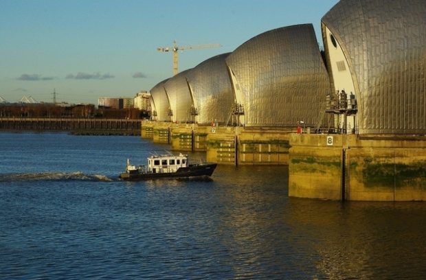 Motorised boat sailing into the Thames Barrier on a sunny day