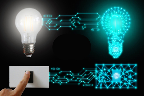 Photograph showing a hand pressing a light switch connected by digital circuit lines to a traditional light bulb and a glowing blue digital light bulb icon.