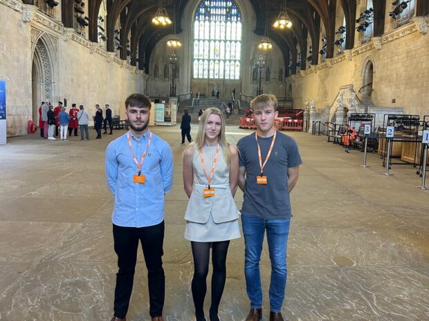 Three apprentices stood inside the Houses of Parliament