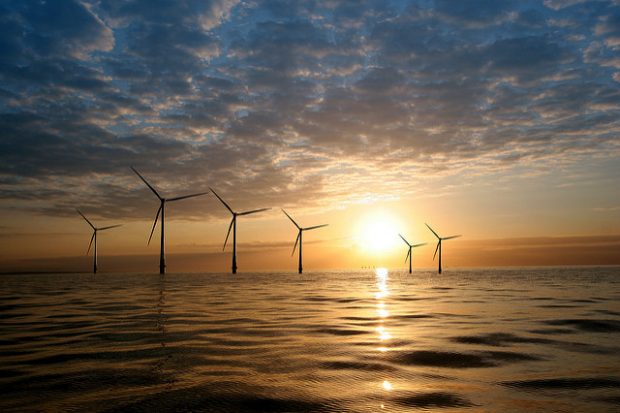 Wind turbines at sea with a sunset.