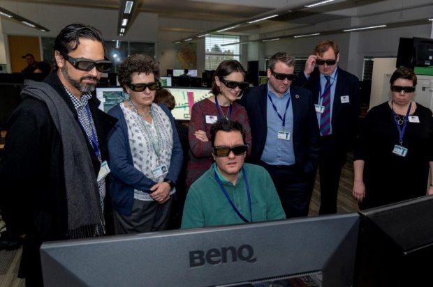 The Geography in Government team staring at a computer screen with 3D glasses.