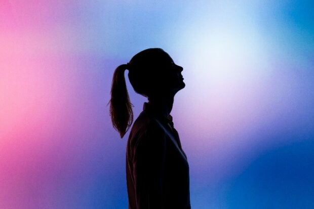 Silhouette of a woman looking up at blurred coloured lights.