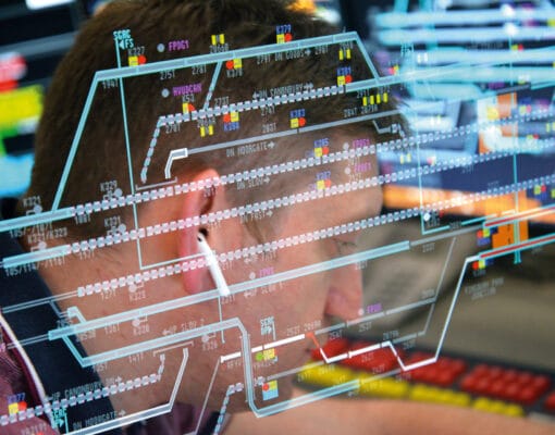 A man working at his desk in front of digital screens with his earphones in