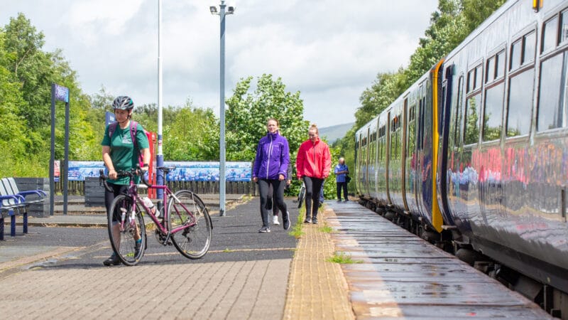 Passengers leaving a train at a sunny station