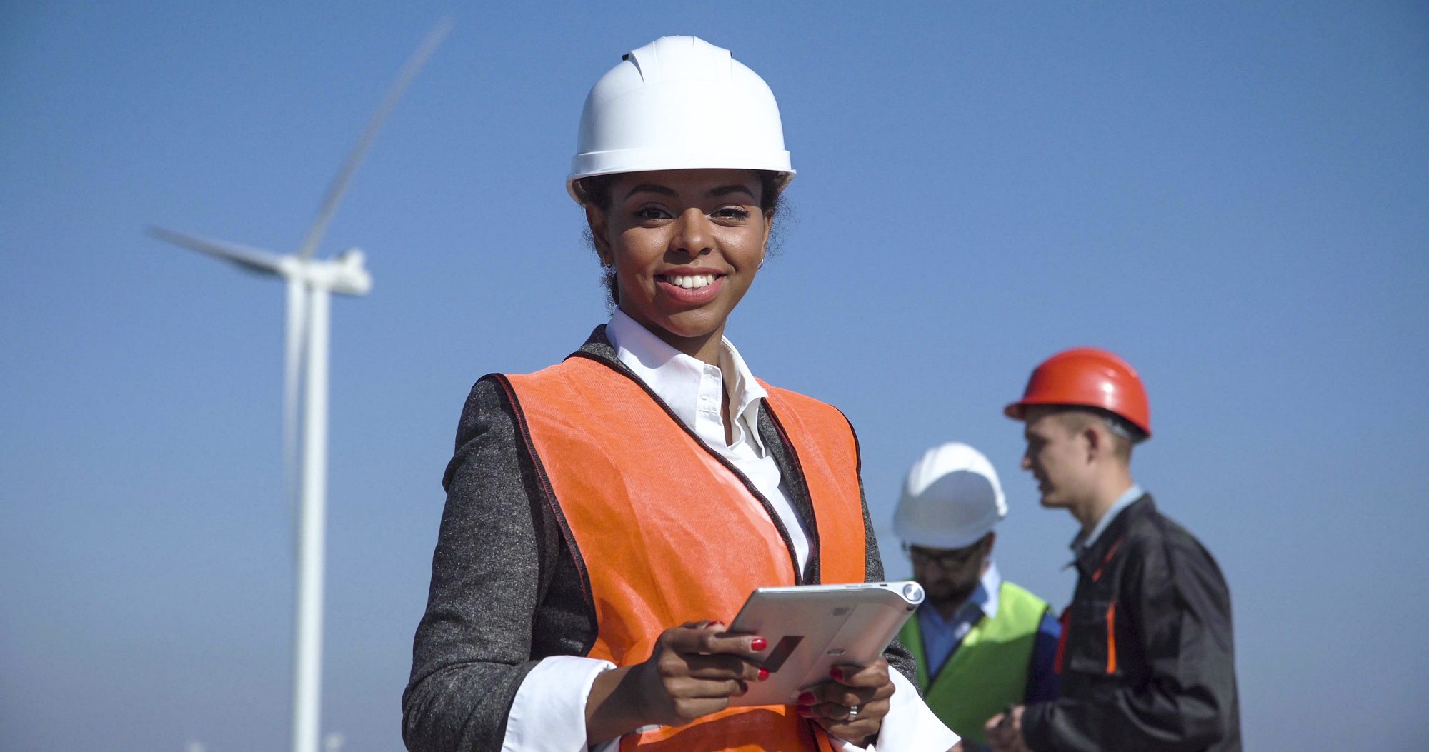 Woman With hard hat Against Wind Turbine