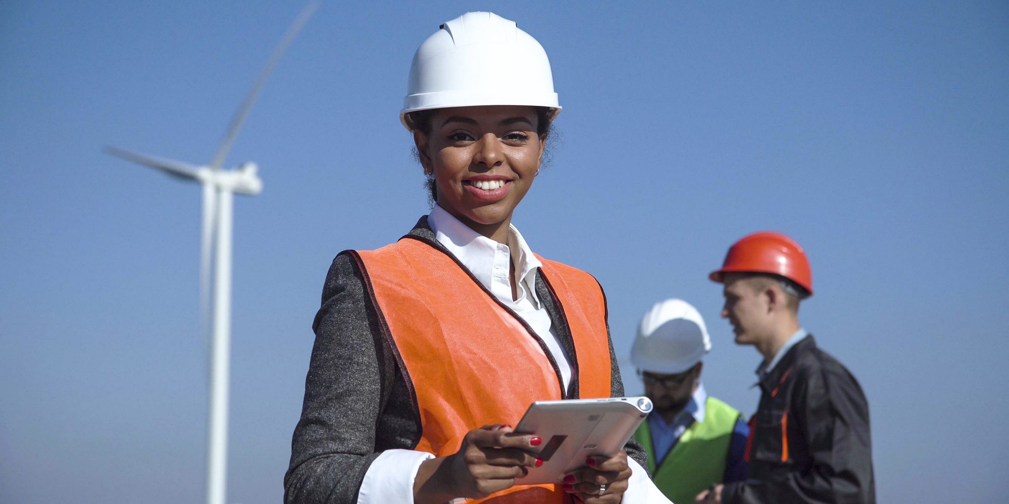 Woman With hard hat Against Wind Turbine