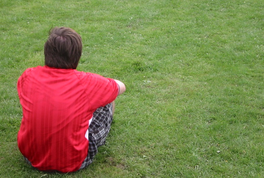 Young man sitting on his own
