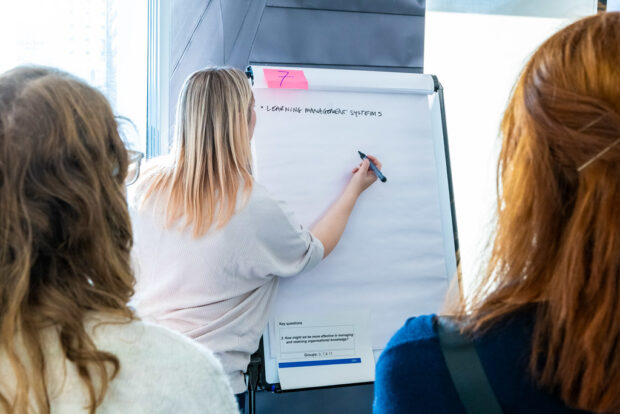 A workshop participant writes ideas on a flipchart during a group discussion.