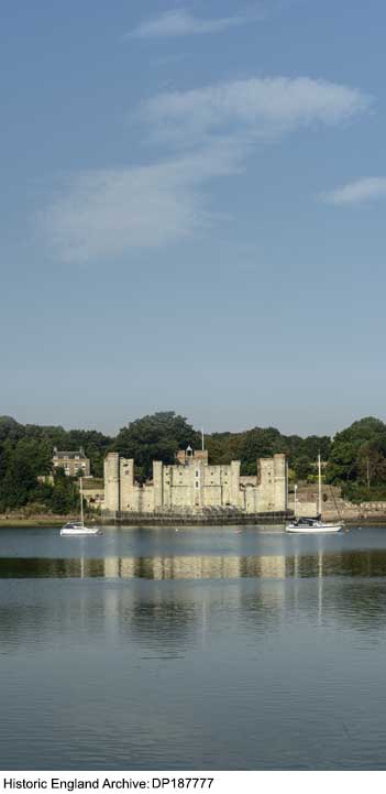 Bottom third of image is blue river, with horizontal reflections, with the white walls of a fortification visible in the distance against a backdrop of green trees. Upper two thirds of image is blue sky.